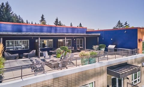 a rooftop patio with furniture and a blue building with a red roof